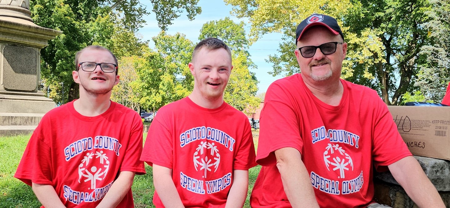 Two Special Olympic athletes and a staff member taking a sit-down break at the Walkathon
